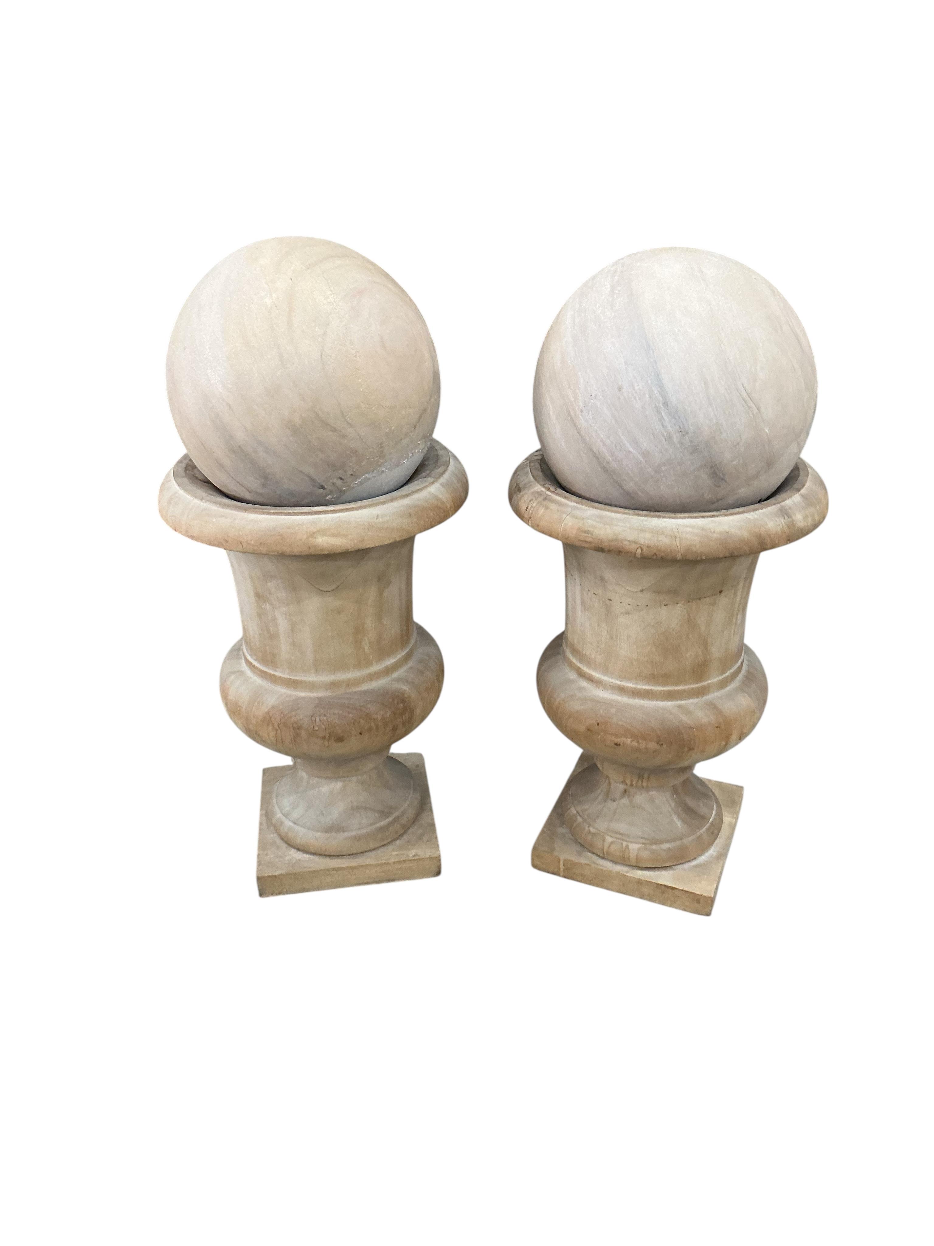 A pair of turned wood urns and composition globes, height 80cm, Provenance: The late Kenneth Turner (1936-2025), celebrity florist, designer and perfume retailer, he received the Royal Warrant from the Prince of Wales in